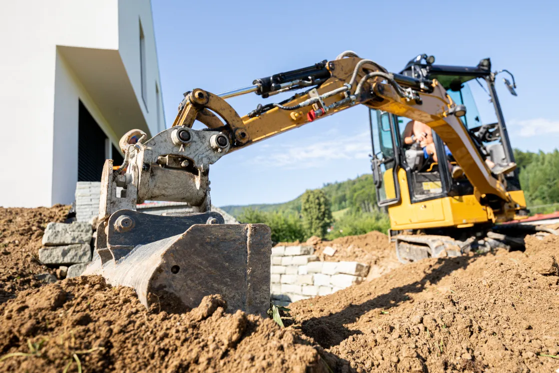 Mini excavator digging preparing ground under home.